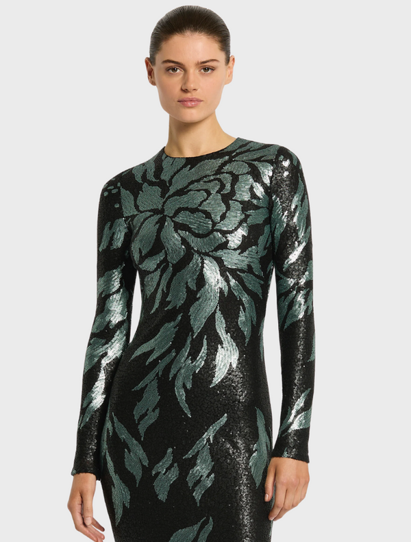A woman models the Larissa Midi Dress in Mint Black, featuring a black base with a vibrant green leaf print.