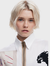 A model is seen wearing a white shirt with an eye-catching abstract design, reflecting a unique fashion statement.

