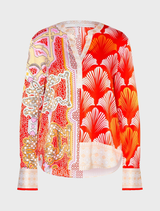 A woman wearing a bright tomato multi blouse paired with pants, highlighting her colorful and fashionable attire.