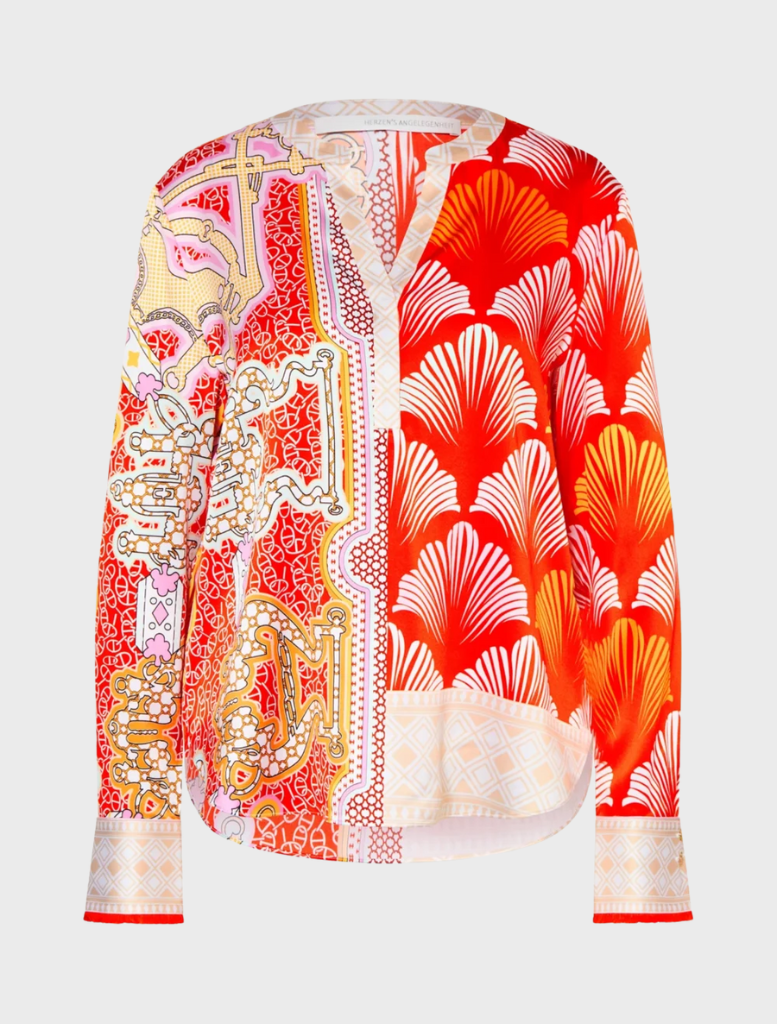 A woman wearing a bright tomato multi blouse paired with pants, highlighting her colorful and fashionable attire.