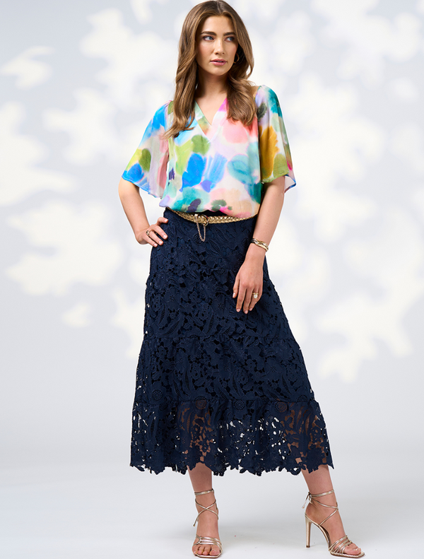 A woman wearing a vibrant, multi-colored top and skirt, showcasing the Free Spirit Top - Multi design.