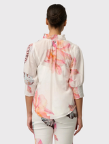 The Oleander Cotton Silk Blouse showcases a shirred collar, a V-neckline, and three-quarter puff sleeves adorned with the Nautilus Bloom pattern.