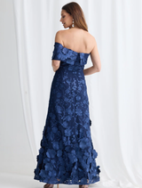 Trellis Lane's navy maxi dress showcases 3D floral fabric, off-shoulder style, and an asymmetric hem for a stylish look.