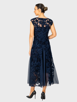 Navy cap sleeve gown with rosette accents and a godet skirt, offering a graceful and stylish appearance.