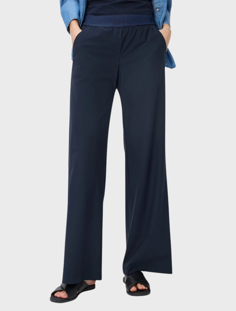 A model dressed in a blue shirt and navy wide pants, presenting a contemporary and casual look.