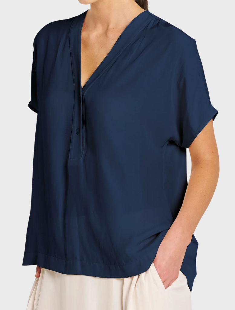 A model showcases a navy shirt and a white skirt, highlighting a contemporary and elegant ensemble.
