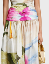 The model wears a lovely floral print dress, featuring an assortment of colorful flowers on a light backdrop.