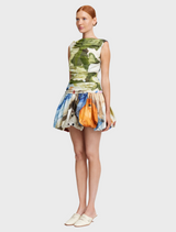 The model is dressed in a stylish skirt adorned with a colorful floral pattern, emphasizing a chic look.