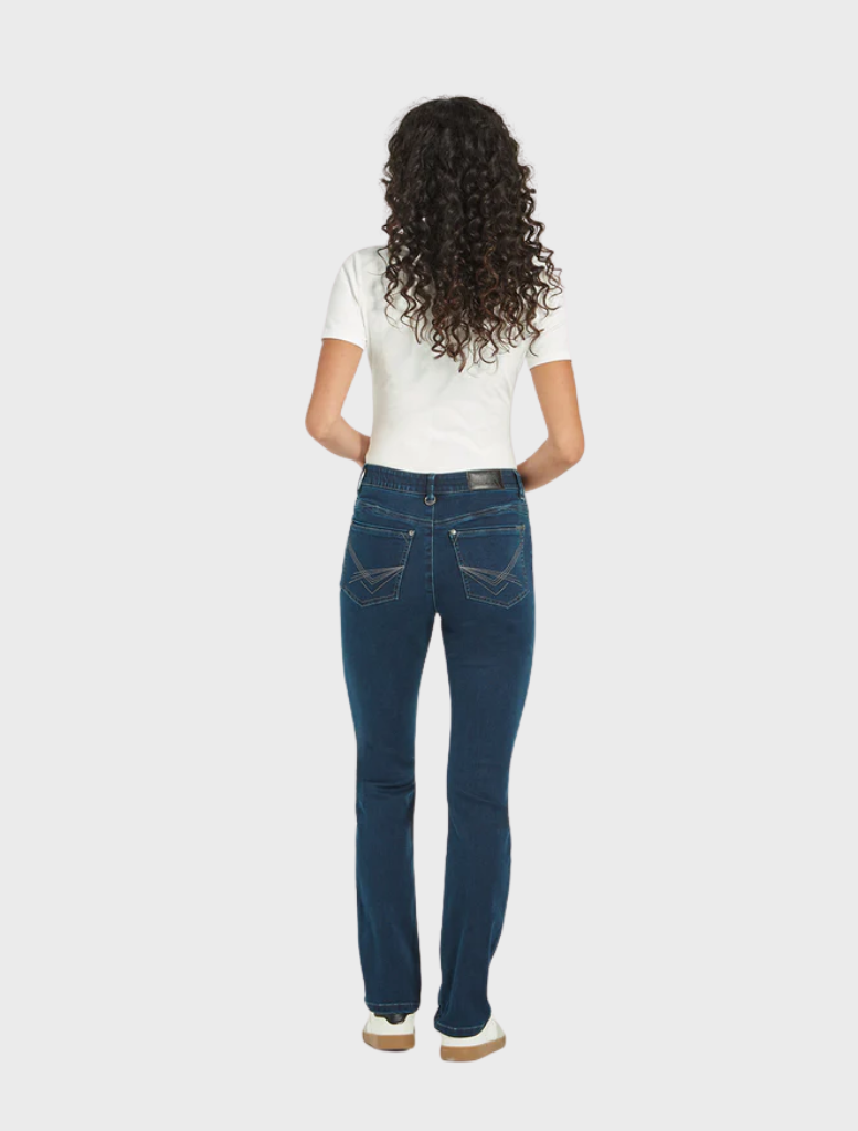 The model is wearing a crisp white shirt paired with blue jeans, presenting a relaxed and fashionable look.