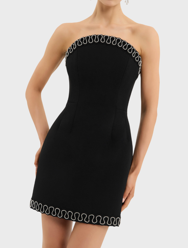 A woman models a black strapless mini dress, complemented by a sleek silver chain.
