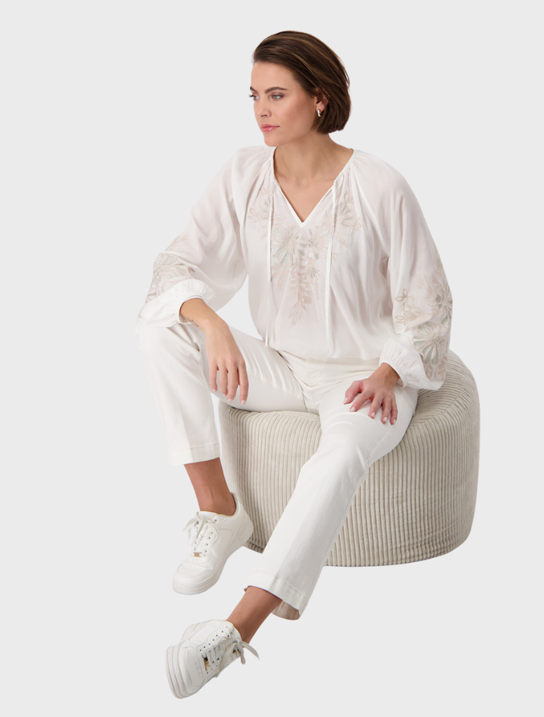 Stylish white blouse embellished with embroidered flowers, offering a fresh and feminine look.