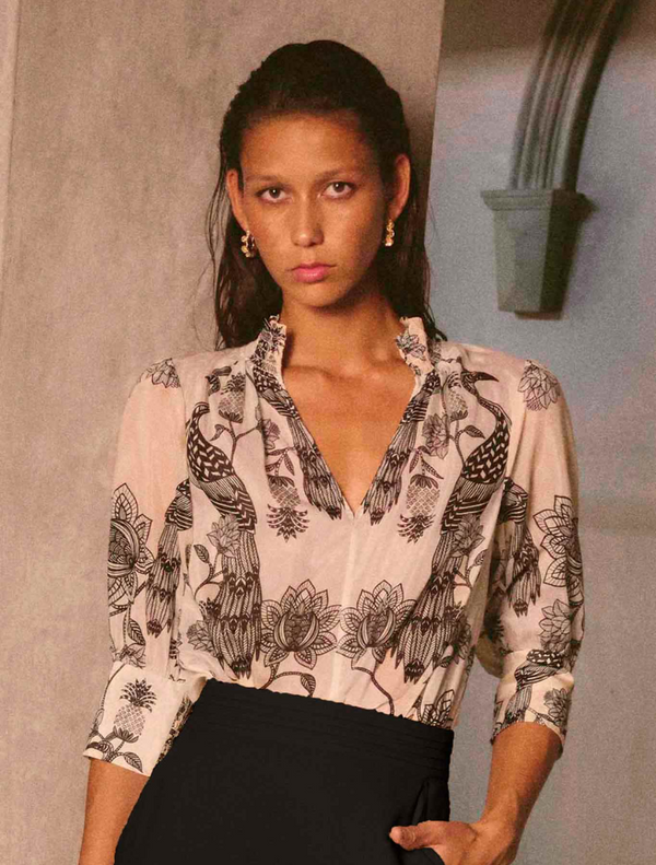 A woman wearing a floral blouse and black skirt, showcasing the Oleander Placement Print Cotton Silk design.