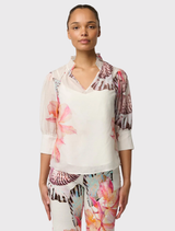 The Cotton-silk Oleander Blouse presents a V-neck, shirred collar, and puff sleeves, accompanied by a detachable slip for added coverage.