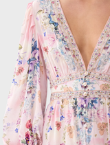 The image features a model in a floral print dress with frills and buttons, designed by Palapast, exuding a fresh vibe.
