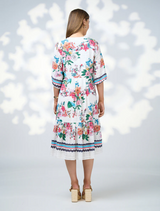 The model wears the Pandora Dress - White Multi, a white floral dress with a stylish v-neckline.
