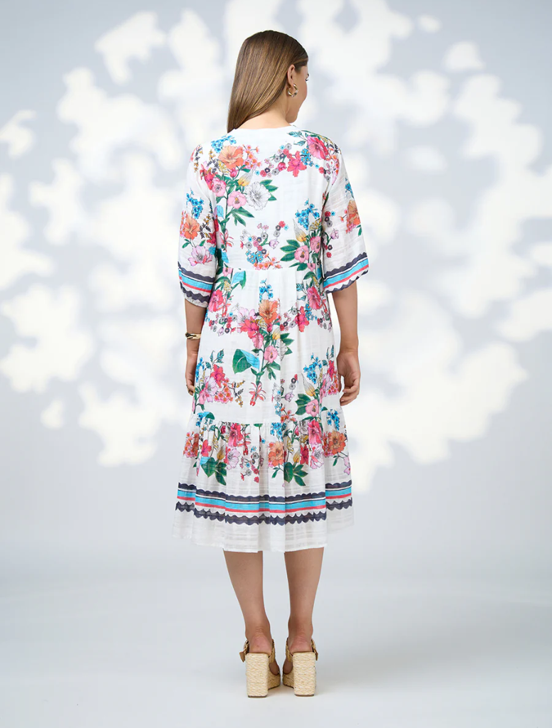 The model wears the Pandora Dress - White Multi, a white floral dress with a stylish v-neckline.