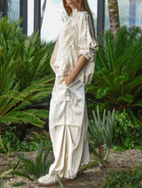 Cream statement pant featuring a shiny finish, elastic waistband, and adjustable hem for a stylish, comfortable fit.