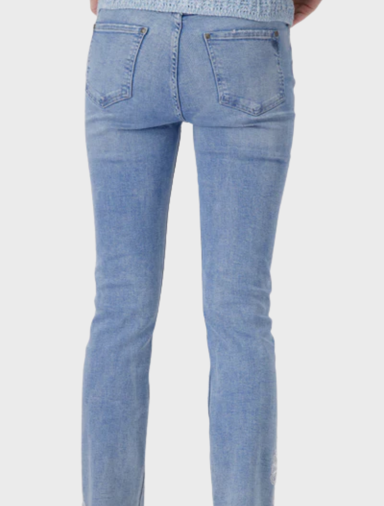 A woman dressed in jeans with elegant lace embellishments, highlighting a blend of casual and chic fashion in a plain setting.