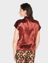  A dark red satin woven top hangs, highlighting its rich color and luxurious fabric.