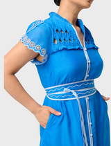  A woman wearing a blue dress with a white collar, showcasing the Petite Xanthia Diamond Smock Yoke design.