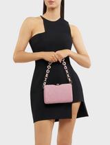 A woman in a black dress holds a pink Birdie Textural Handle Bag, showcasing a stylish contrast in her outfit.