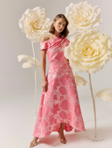 Pink floral asymmetrical maxi gown displayed on a mannequin, showcasing its elegant design and vibrant colors.