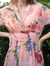 Elegant pink dress adorned with a floral print, featuring a fitted top and flowing skirt, perfect for spring occasions.