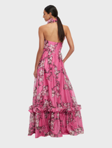 Feminine pink magnolia print maxi dress with a halterneck and ruffled design, ideal for summer events.