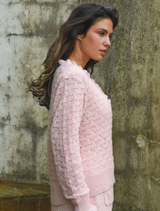 Soft pink cardigan with ruffled detailing on the front and sleeves, ideal for adding a feminine touch to any outfit.