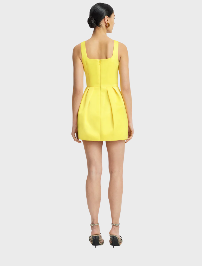 The model wears a sunny yellow dress decorated with flowers, presenting a fresh and stylish look.
