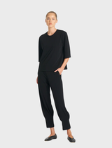 Black Plaza Crew Top displayed on a hanger, showcasing its simple and stylish design.