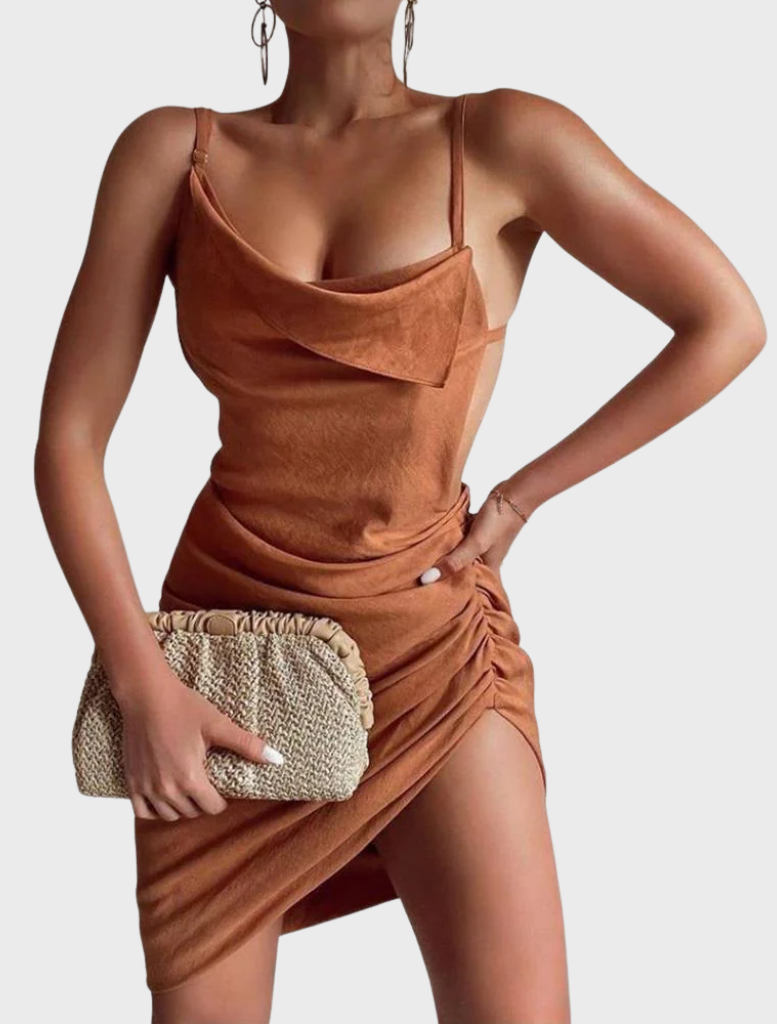 A woman wearing a brown dress carries a gold-accented Amalia pleated woven clutch in natural tones.