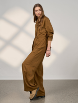 Close-up of bronze Polaris Pant, highlighting its smooth fabric and tailored fit against a neutral backdrop.