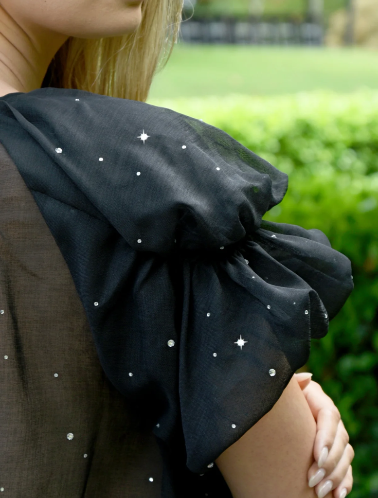 A woman wearing a black top paired with brown pants, presenting a simple and chic look.