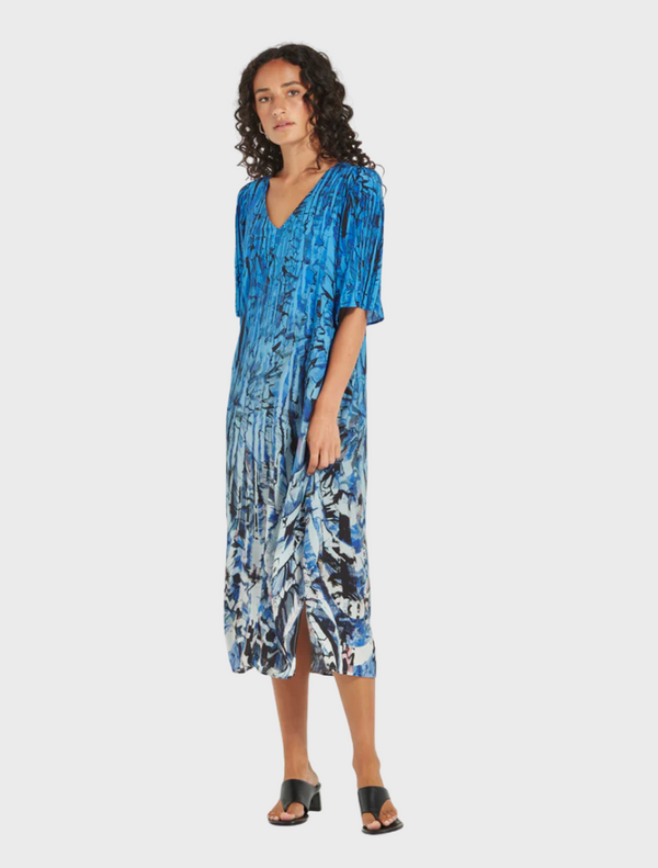 A woman models a blue and white floral print dress, highlighting the delicate design and colors of her outfit.
