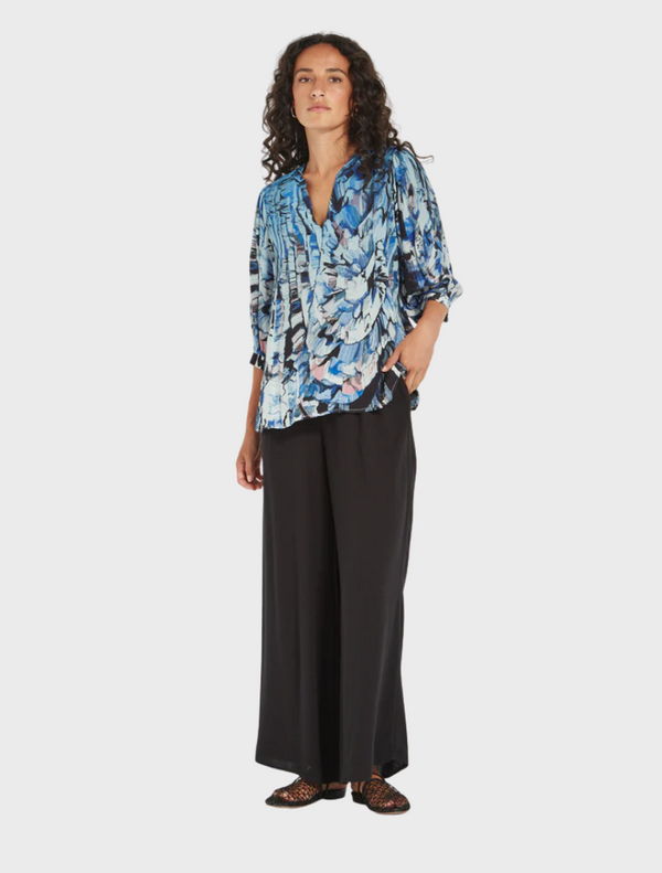 The model displays a blue and black top adorned with a floral print, emphasizing a trendy and fashionable look.