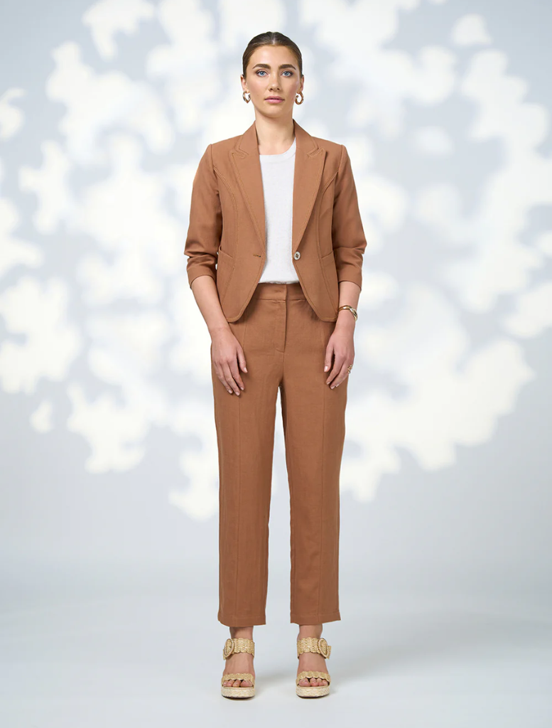 Quinn pants in a warm toffee shade, featuring a smooth fabric and a chic silhouette against a neutral backdrop.