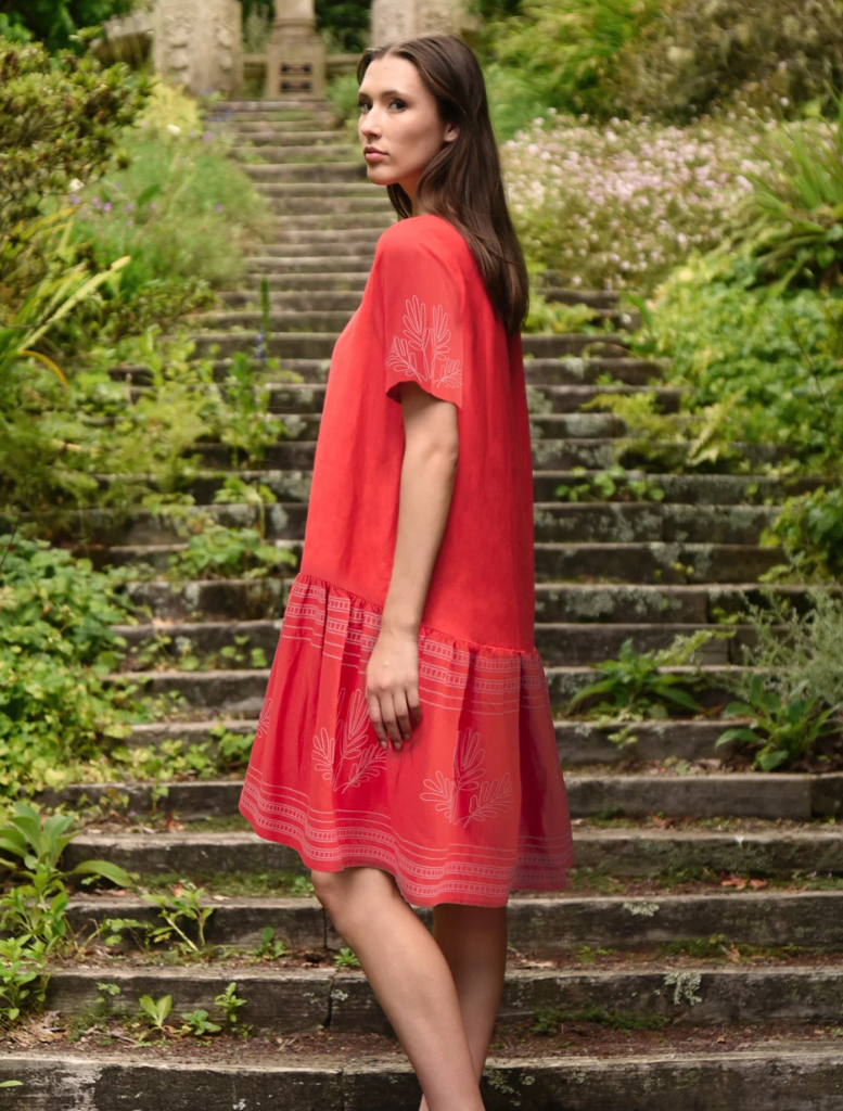 woman wearing a striking red dress stands on steps, exuding grace and style in her poised stance.