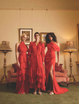 Three women pose lowing red dress with ruffled sleeves, designed to create a dramatic and eye-catching silhouette.