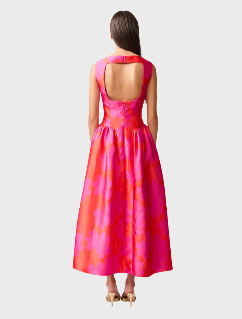 A woman in a stylish pink and red dress poses confidently, highlighting the dress's bold color combination and design.