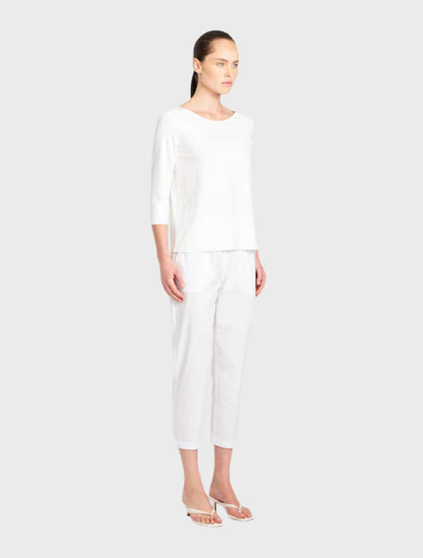A white relaxed boat neck shirt draped elegantly, highlighting its comfortable fit and simple design.