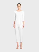 White relaxed boat neck top displayed on a hanger, showcasing its soft fabric and casual style.