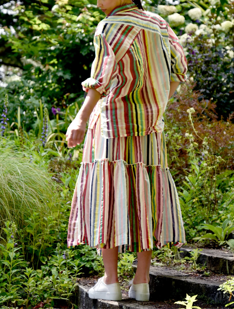  A woman in a striped dress walks leisurely on a path through a natural setting.