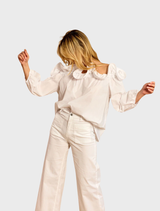 Close-up of a white Riva ruffled shirt, emphasizing the delicate ruffles and smooth fabric in a well-lit setting.