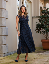 Elegant navy gown with cap sleeves and godet design, adorned with rosette embellishments for a sophisticated look.