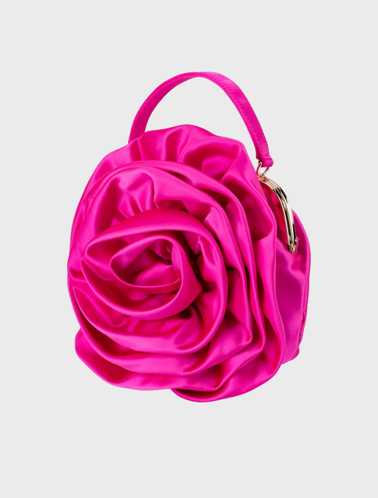 The Rosita Rosette Frame Bag in fuchsia, a pink satin flower bag, suspended from a stylish chain.