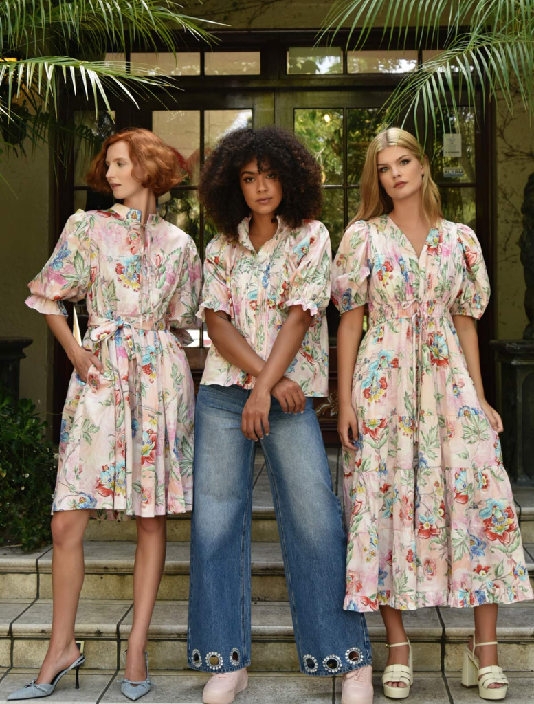 A model displays a beautiful floral dress, rich with colorful patterns, ideal for a warm-weather event.