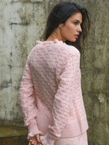 Elegant pink cardigan adorned with ruffles, designed for comfort and style, suitable for various occasions.