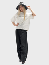 A pair of black trousers with a rusty finish, highlighting their distressed look and fashion-forward design.