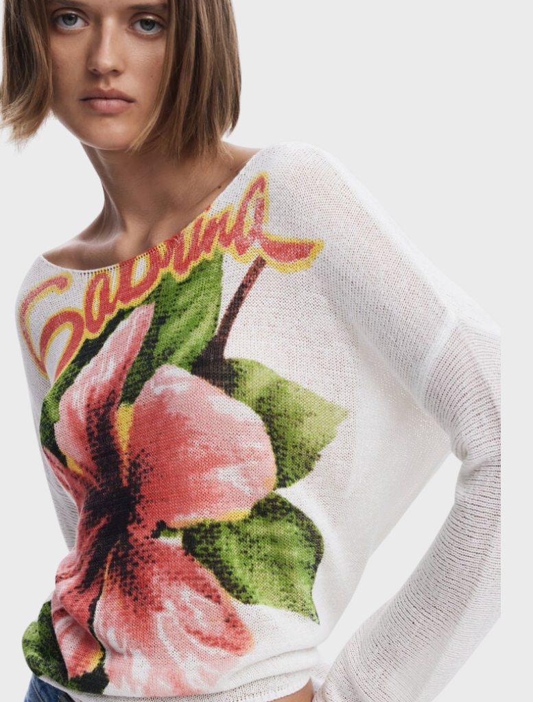 A model wears a white sweater embellished with a delicate floral motif.